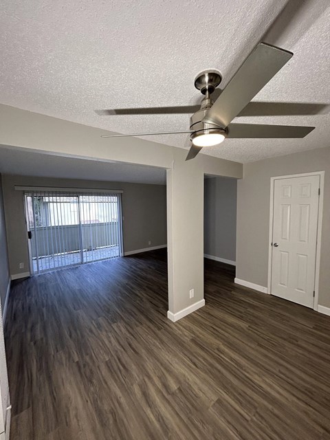an empty living room with wood flooring and a ceiling fan
